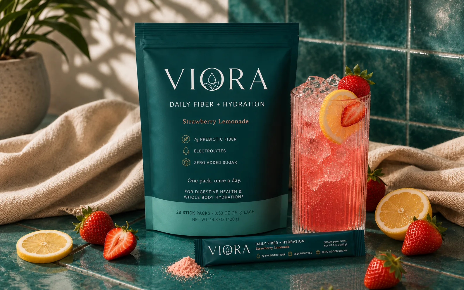 Viora pouch and torn stick pack beside a ribbed glass of strawberry lemonade over ice