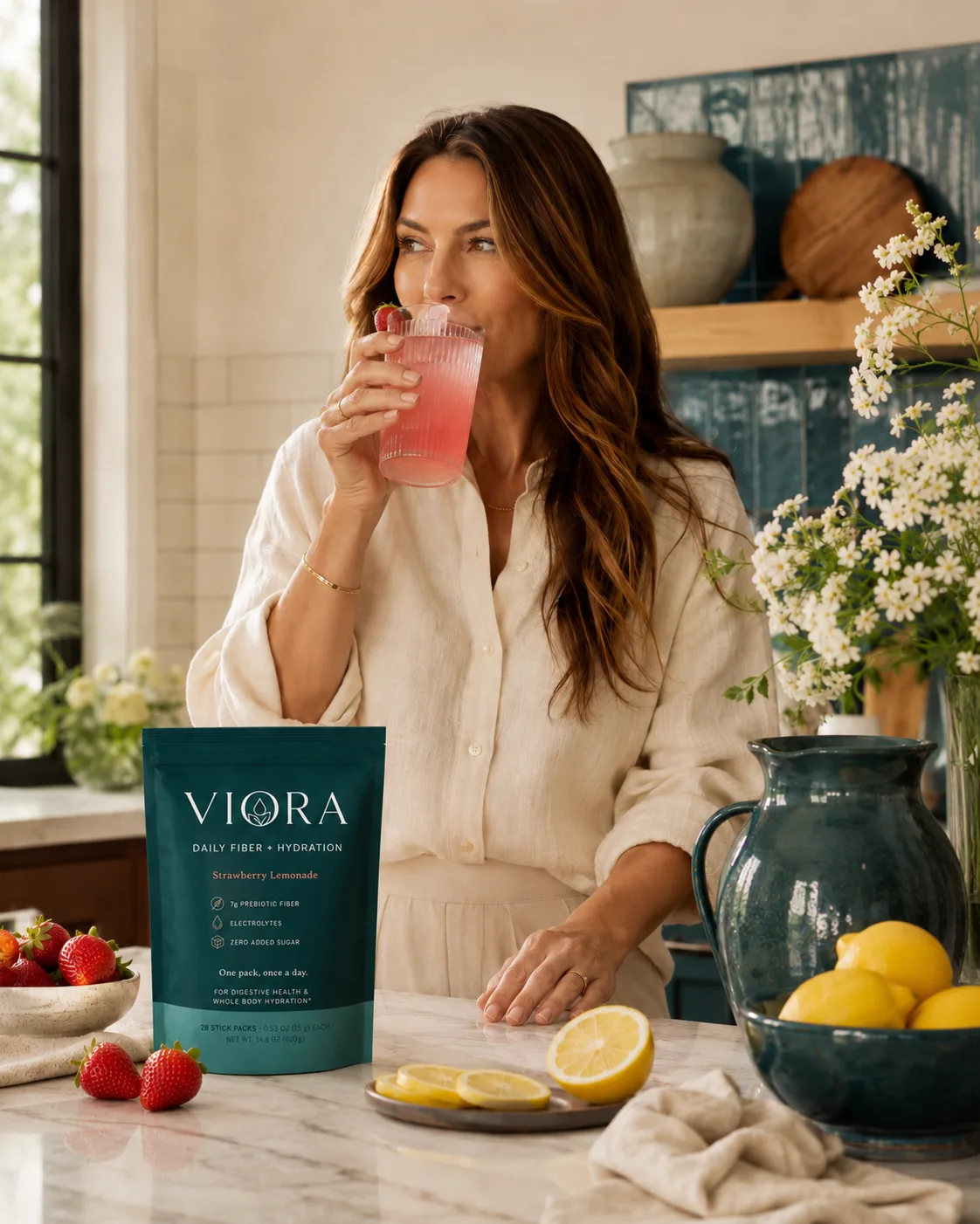 Woman enjoying a glass of Viora strawberry lemonade at a bright kitchen counter